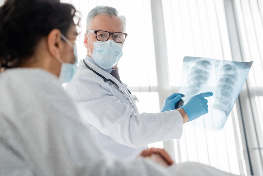 Lekarz pokazujący pacjentce zdjęcie rentgenowskie płuc.