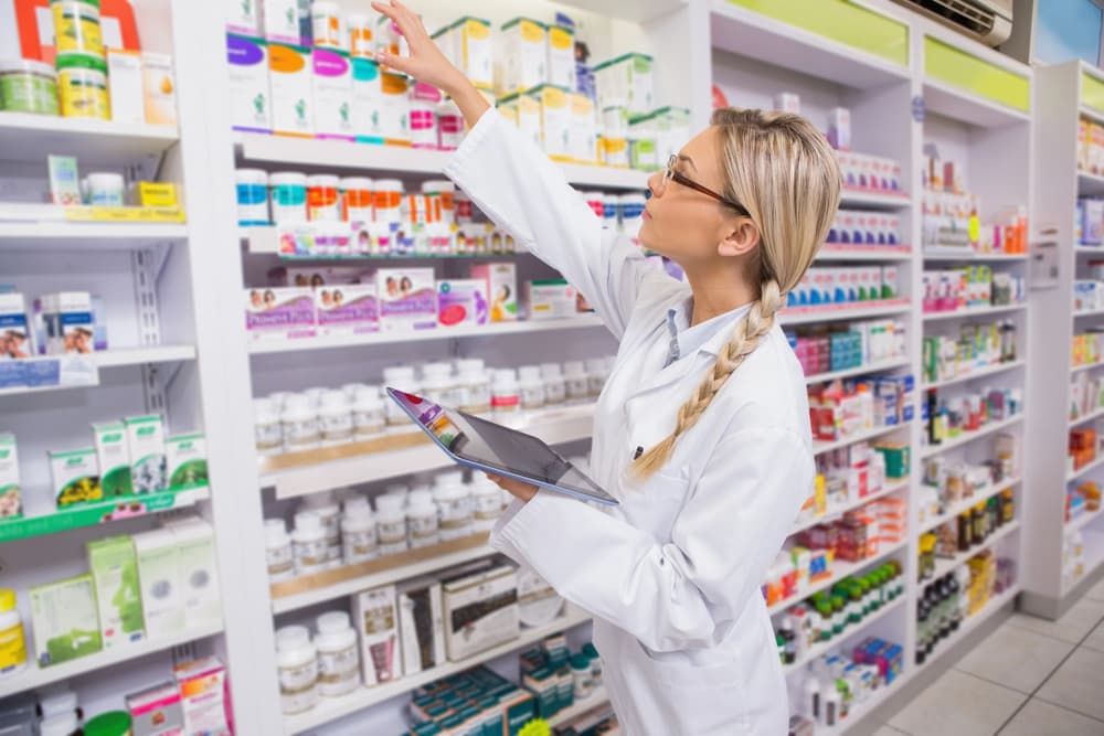 farmaceutka sięgająca w aptece po lek z półki 