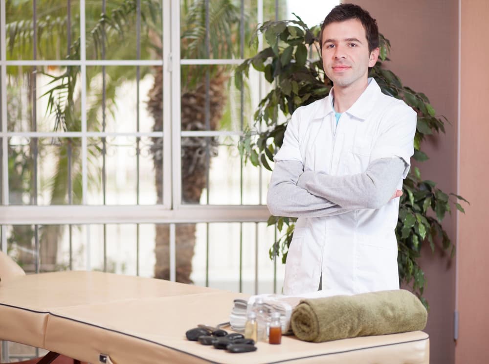 Naturopata w swoim gabinecie przy łóżku do masażu.