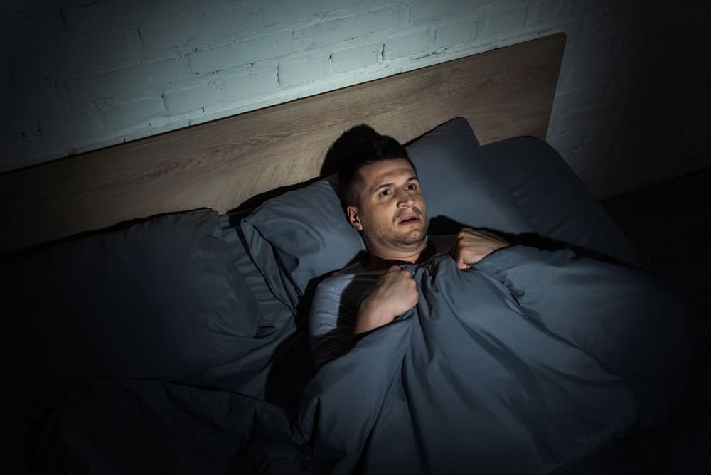 przerażony mężczyzna leżący nocą w łóżku przerażony mężczyzna leżący nocą w łóżku