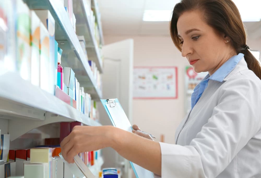 farmaceutka szukająca leku na półkach w aptece farmaceutka szukająca leku na półkach w aptece