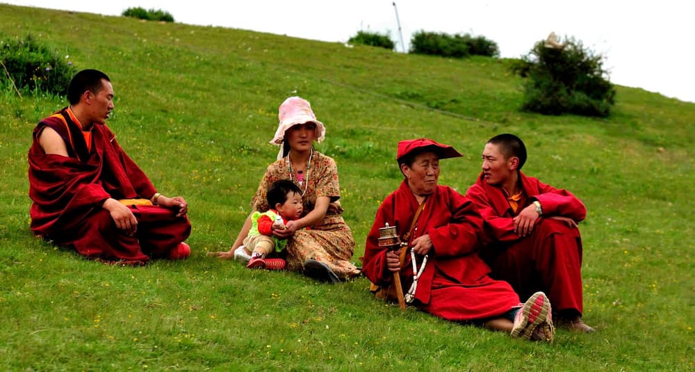 Poliandria w Tybecie – trzech tybetańskich mężczyzn i jedna kobieta z dzieckiem siedzący na trawie. Poliandria w Tybecie – trzech tybetańskich mężczyzn i jedna kobieta z dzieckiem siedzący na trawie.