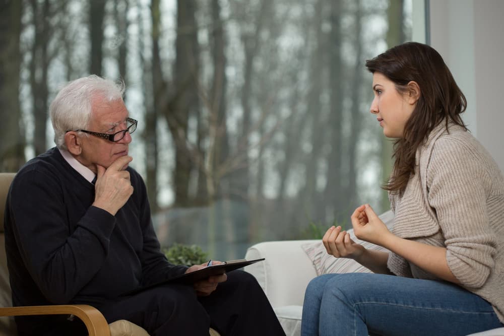 starszy psychiatra rozmawiający z młodą pacjentką starszy psychiatra rozmawiający z młodą pacjentką