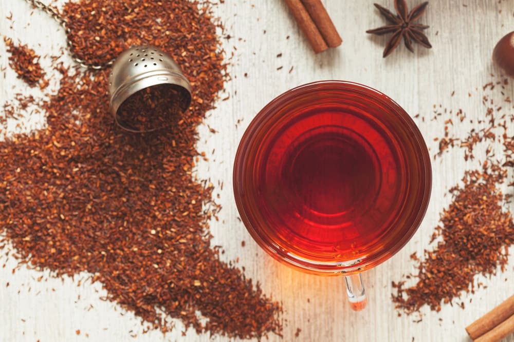 Filiżanka z herbatą rooibos z rozsypanym obok suszem herbaty rooibos. Filiżanka z herbatą rooibos z rozsypanym obok suszem herbaty rooibos.