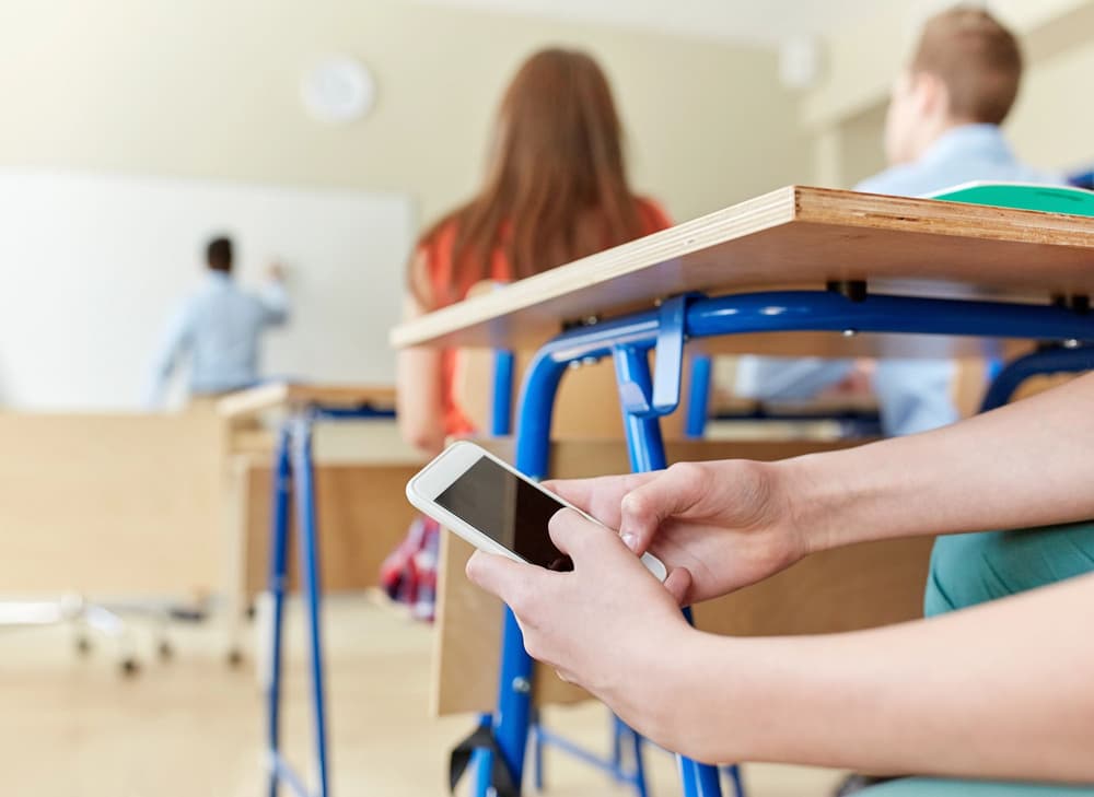 uczeń korzystający z telefonu pod ławką uczeń korzystający z telefonu pod ławką