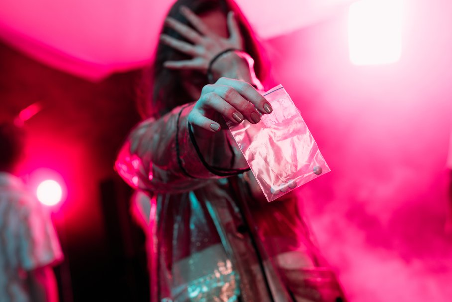 Młoda dziewczyna na imprezie trzymająca woreczek z tabletkami.