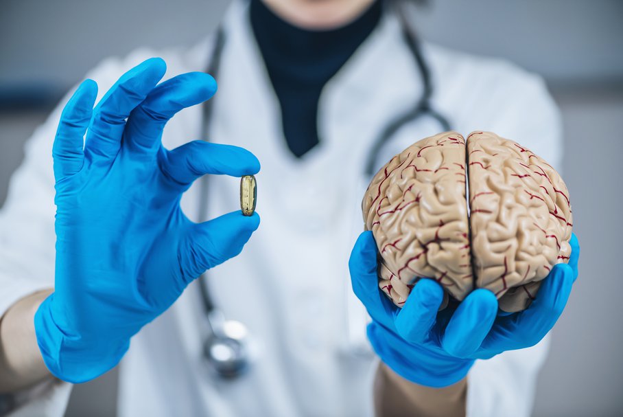 Lekarz pokazujący kapsułkę z lekiem i model ludzkiego mózgu.