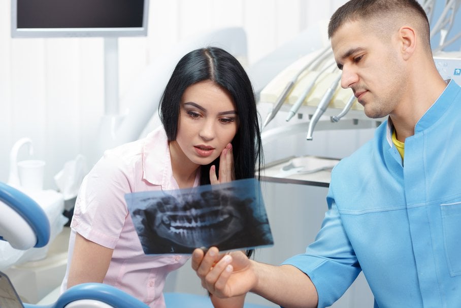 Stomatolog pokazujący zdjęcie rentgenowskie szczęki pacjentce.