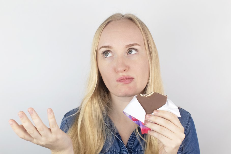 Młoda kobieta z ageuzją jedząca czekoladę.