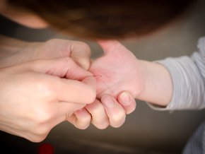 Kobieta wyciągająca drzazgę z dłoni chłopca.