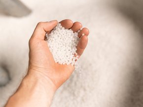 Męska dłoń trzymająca granulat tworzywa sztucznego.