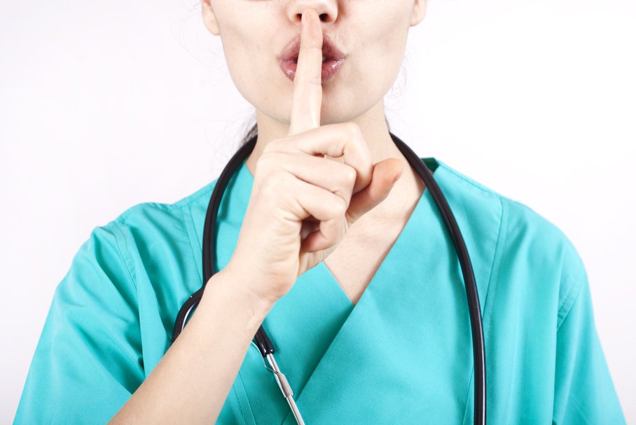 Lekarz trzymająca palec wskazujący na ustach w geście uciszania.