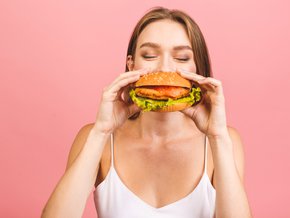 Młoda kobieta jedząca hamburgera.