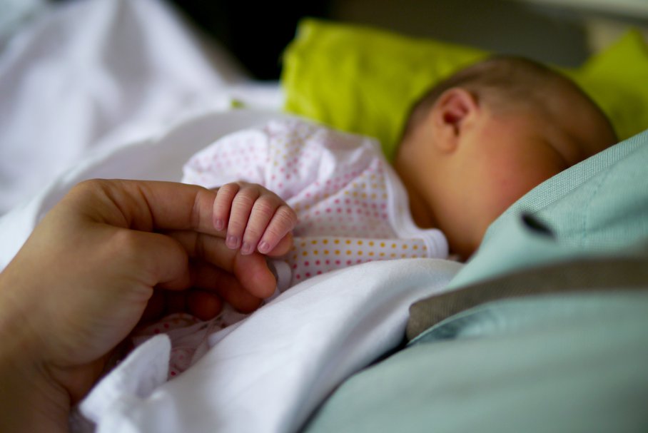 Noworodek trzymający palec rodzica.