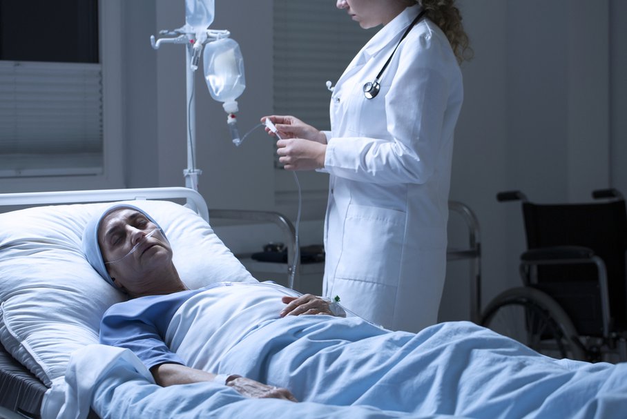 Pielęgniarka sprawdzająca kroplówkę umierającej pacjentki.