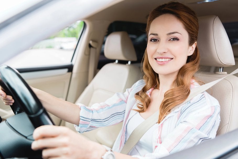 Uśmiechnięta kobieta prowadząca samochód.
