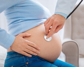 Lekarz badający brzuch ciężarnej kobiety.