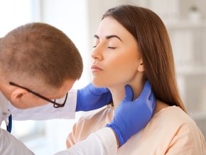 Lekarz diagnozujący zapalenie tarczycy u pacjentki.