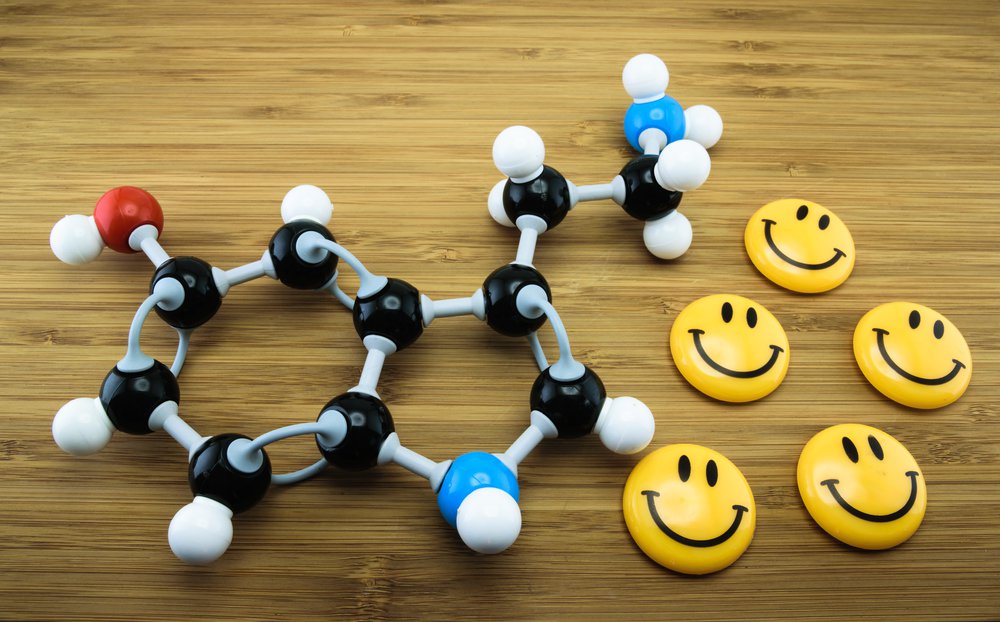 olekularna serotoniny obok uśmiechniętych żółtych emoji