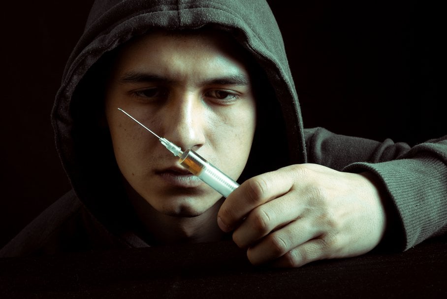 Smutny mężczyzna trzymający strzykawkę z narkotykiem.