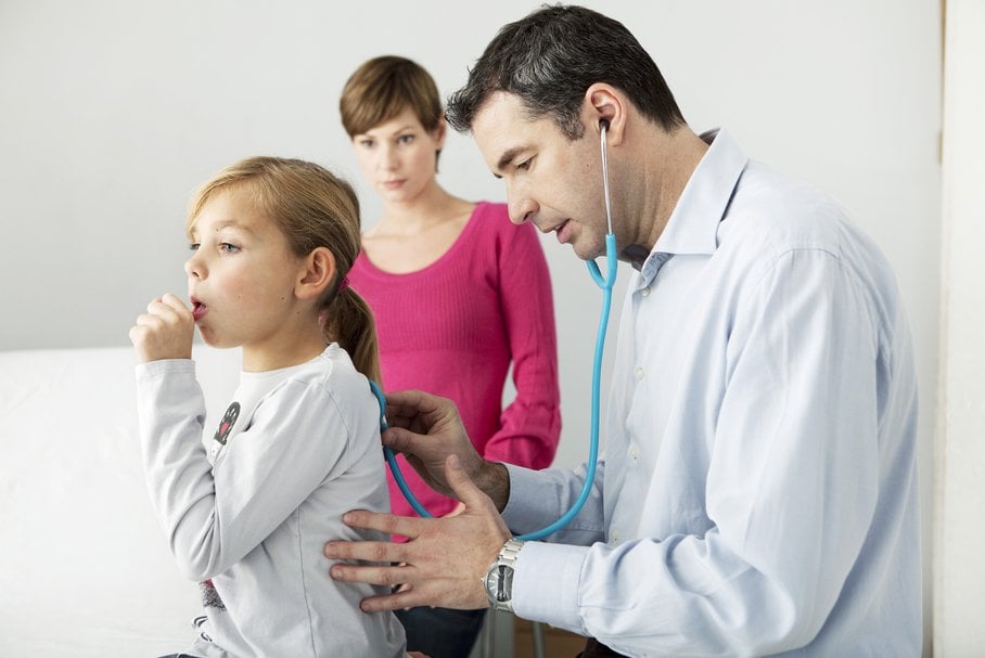 Lekarz osłuchujący stetoskopem małą dziewczynkę.