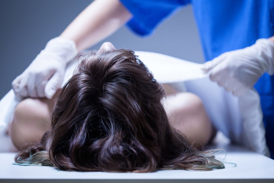 Pracownik kostnicy zakrywający ciało kobiety.